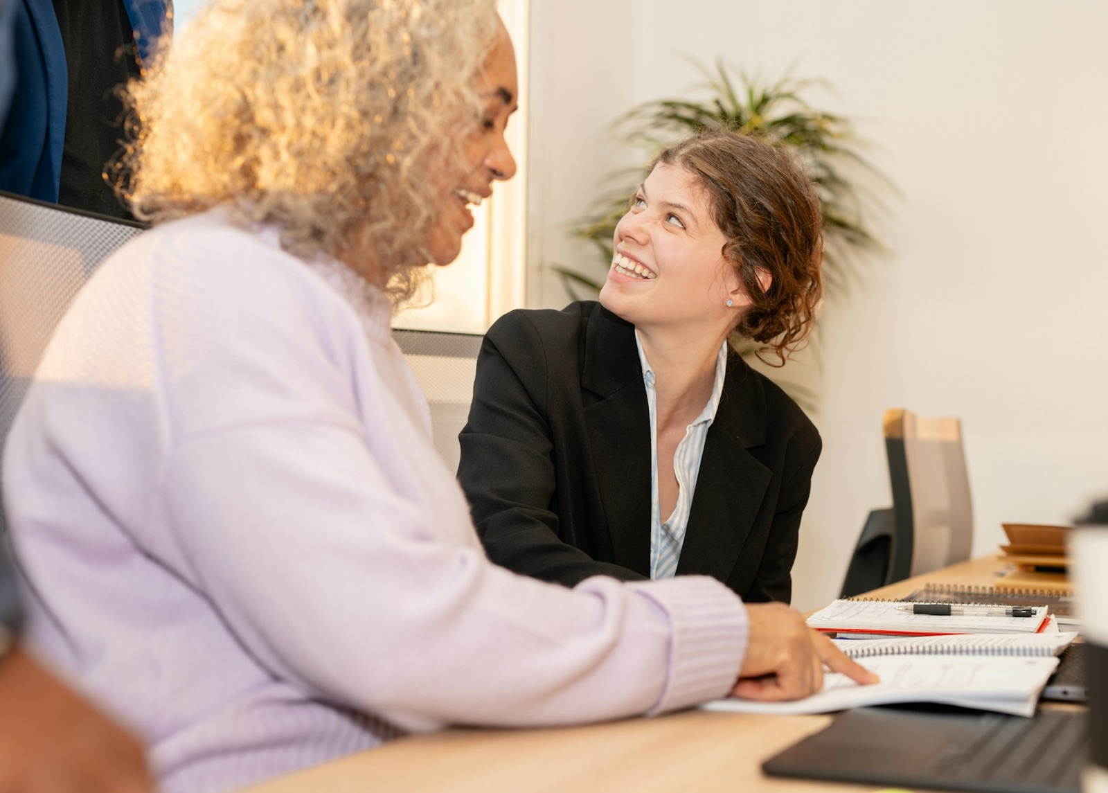 Twee vrouwen aan een bureau die samen papieren doornemen